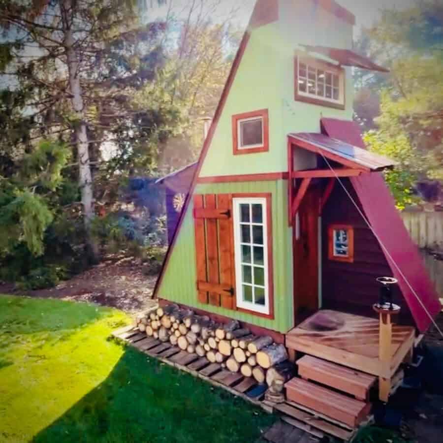 A-Frame tiny house built for off-grid living, featuring colorful exterior and eco-friendly materials.
