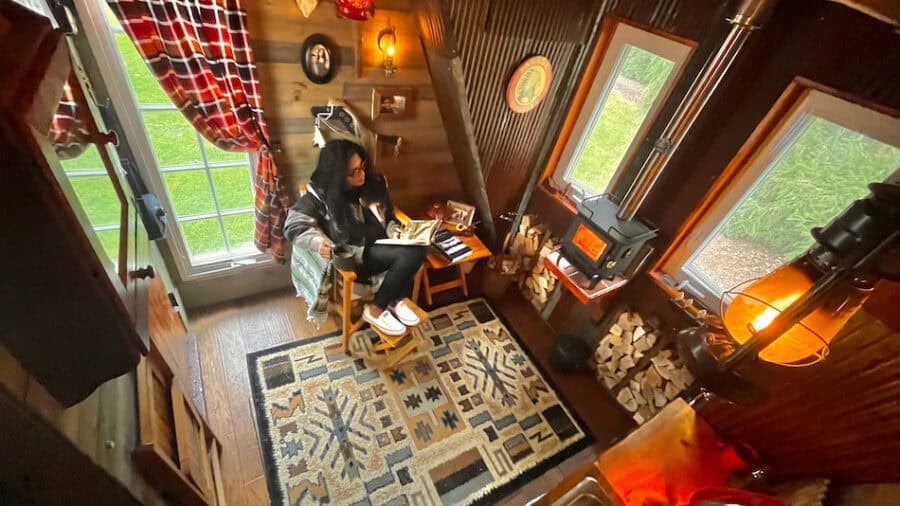 Interior view of Neil's off-grid cabin with cozy furnishings and wood stove.
