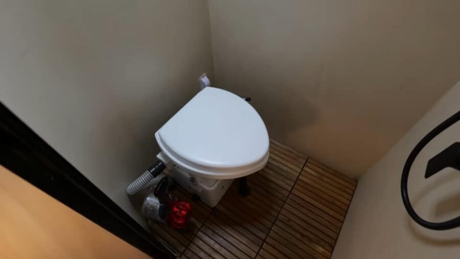 Compact toilet in a tiny house bathroom with wooden flooring.