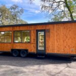 Tiny house on wheels with spacious windows and natural wood finish, perfect for small space living a.