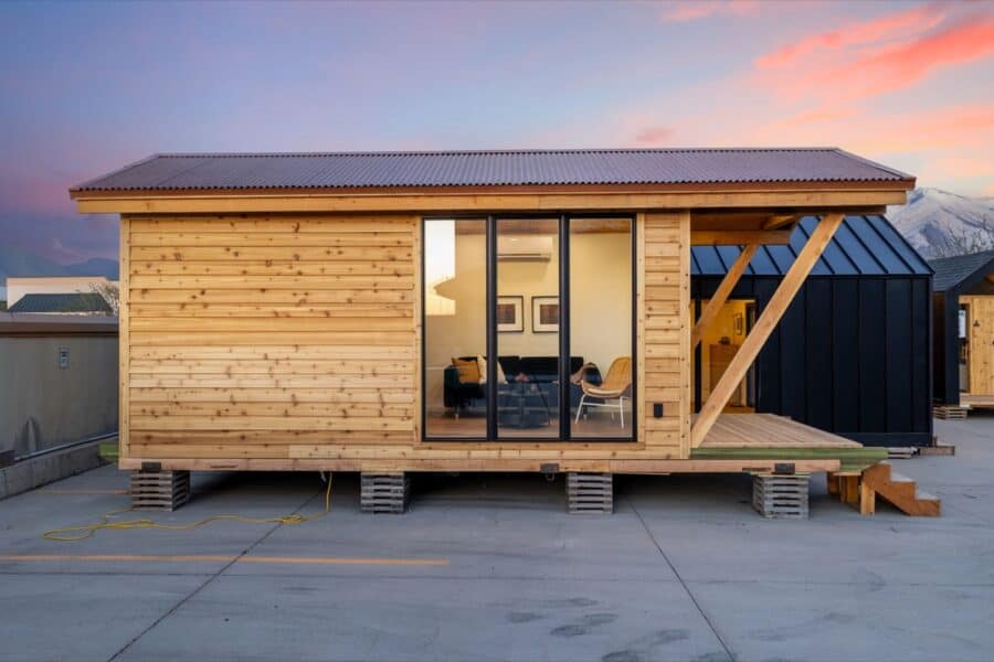 Compact tiny house with wooden exterior and large glass doors.