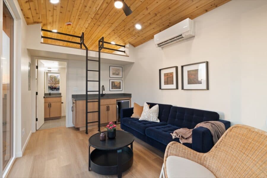 Modern tiny house living space with cozy sofa, loft area, and minimalist design.