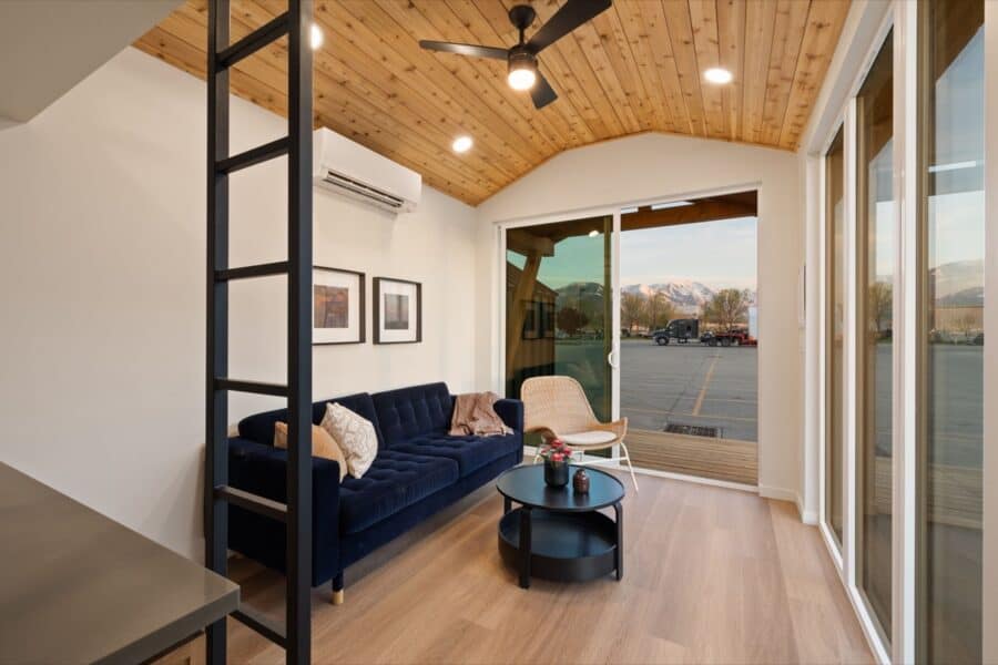 Modern tiny house interior with wooden ceiling and large windows.