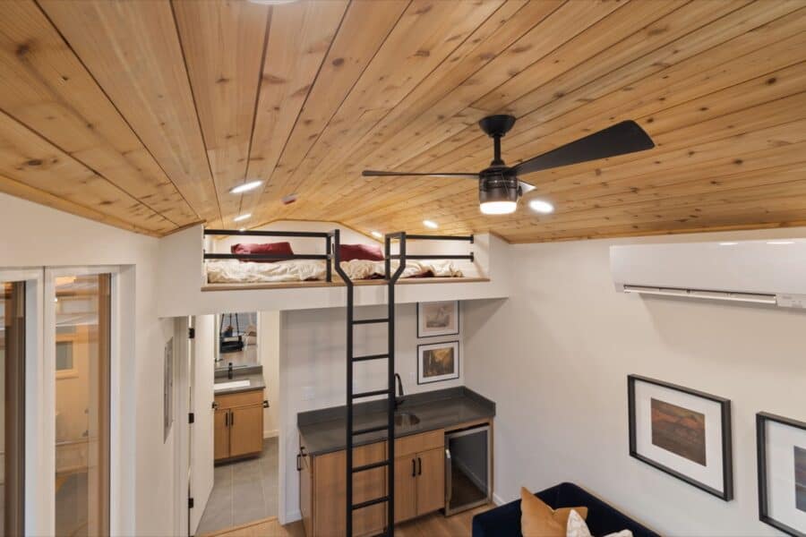 Efficient tiny house interior featuring a cozy loft, wooden ceiling, and modern furnishings for smal.