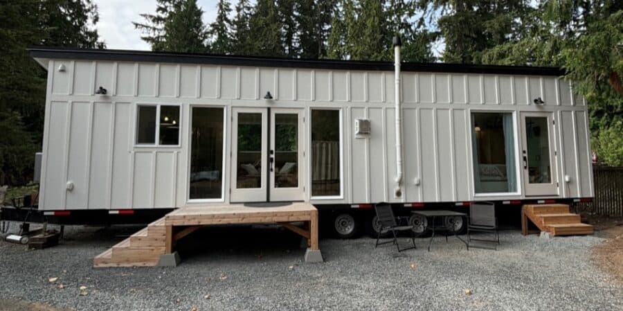 Compact tiny house with large windows and outdoor steps, perfect for small space living.