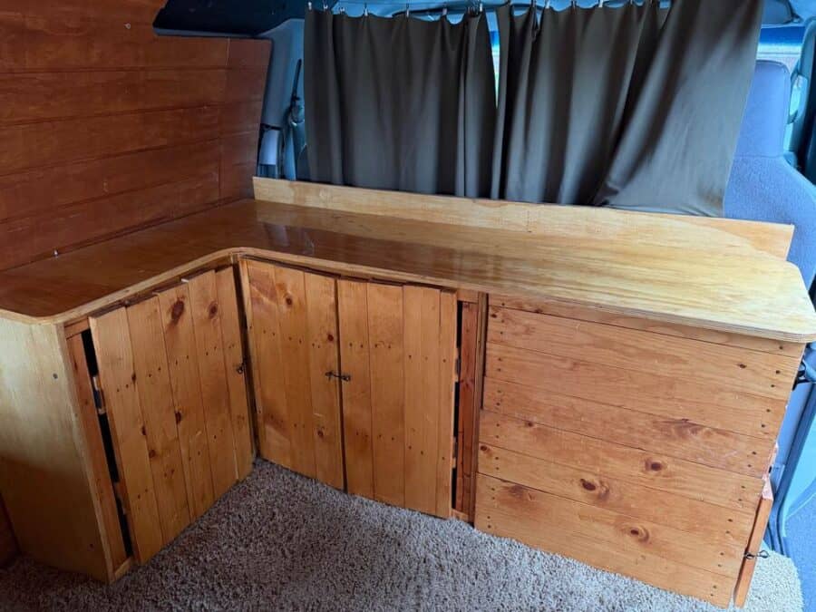 Interior storage cabinets in a Ford E150 campervan for efficient space use.