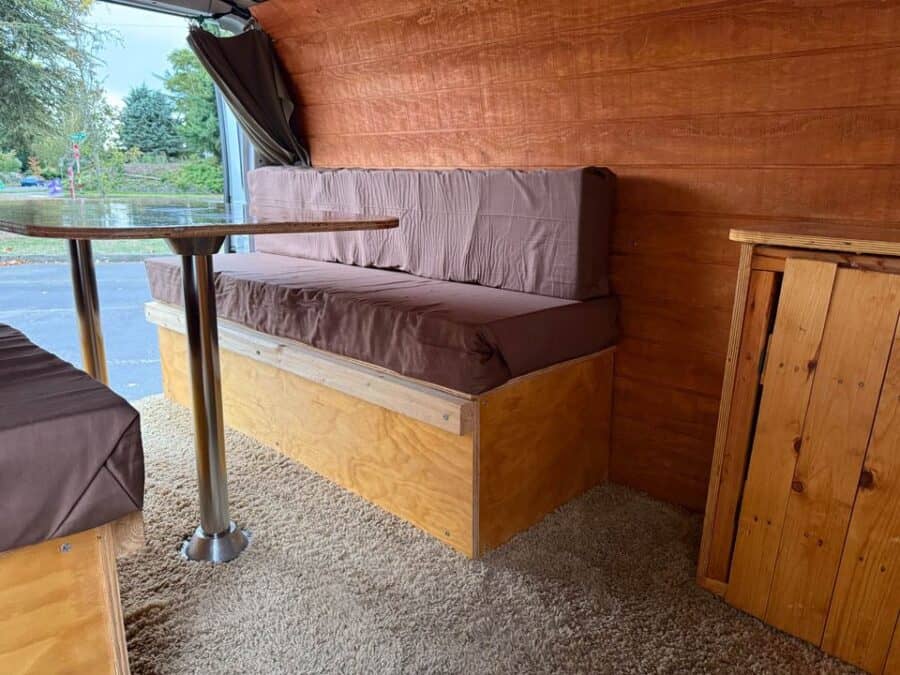 Compact campervan interior with wooden walls and built-in seating for small space living.
