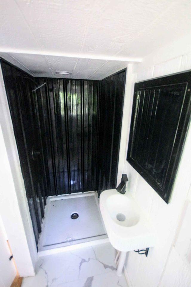 Compact tiny house bathroom with shower and sink.