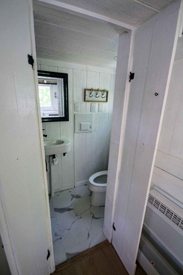 Compact tiny house bathroom with white wood paneling and modern fixtures.