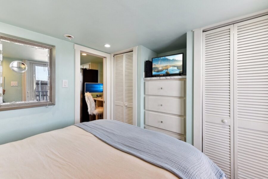 Cozy tiny house bedroom with built-in storage and a flat-screen TV, perfect for small space living n.
