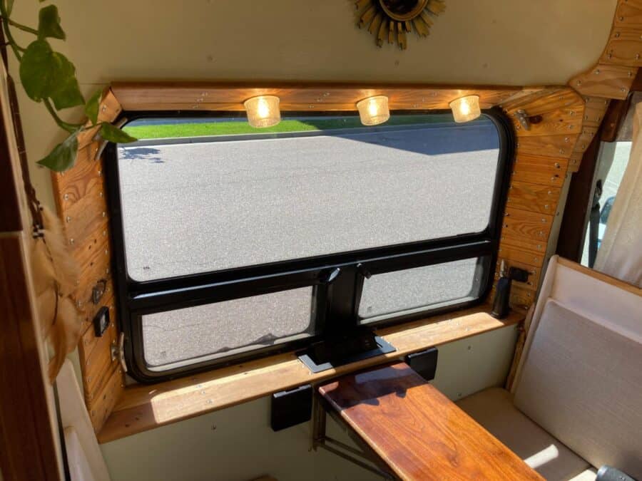 Large window inside tiny house with natural wood trim and cozy seating area.