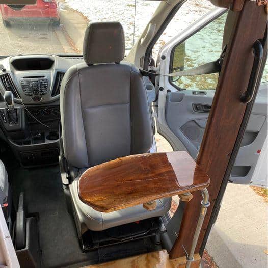 Interior view of a van with a wooden foldable table attached to the seat.