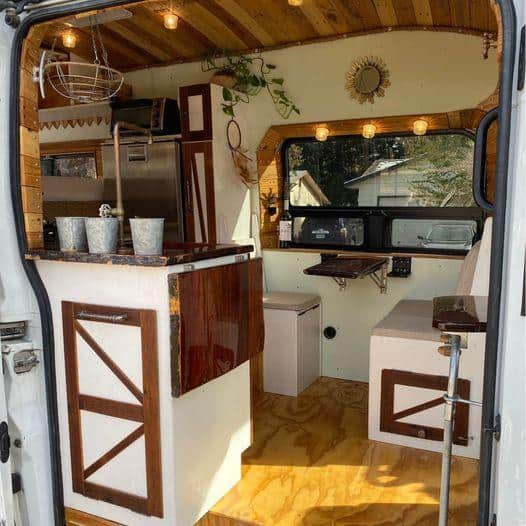 Interior view of a tiny house with a compact kitchen and cozy seating area.