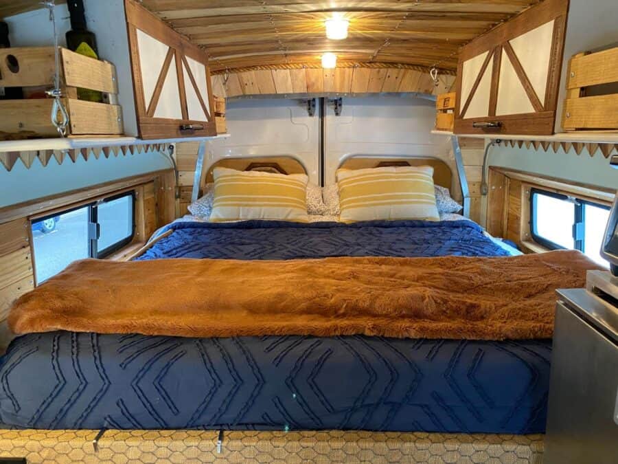 Tiny house bedroom with wooden cabinets and cozy bedding.