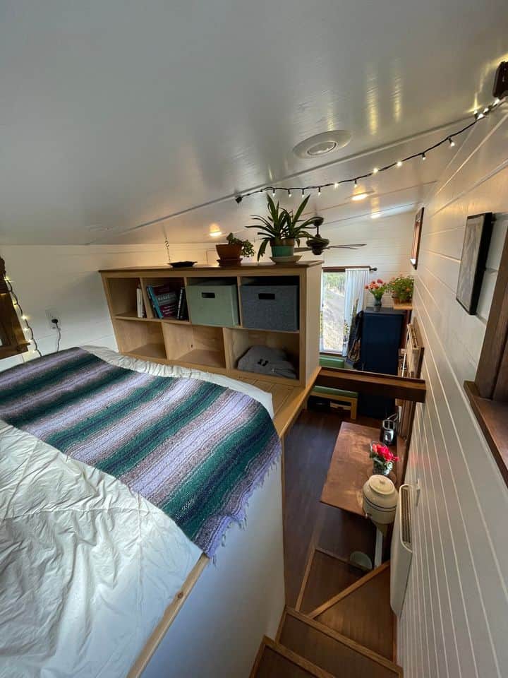 Compact tiny house bedroom with storage and cozy decor.