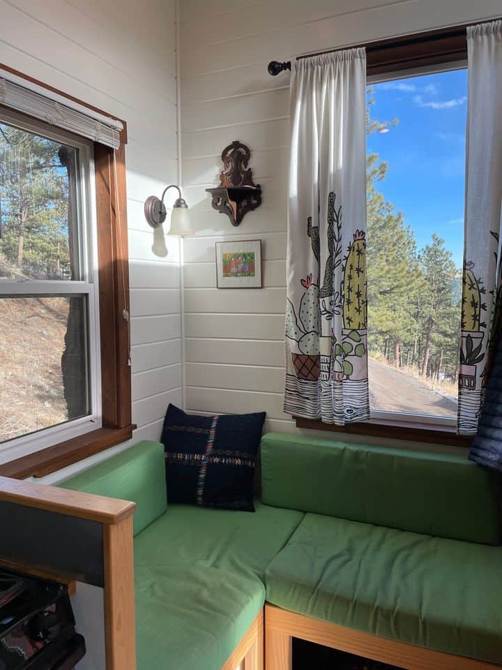 Bright tiny house interior with green seating and large windows.