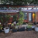 Tiny house exterior with lush potted plants and outdoor seating in Texas.