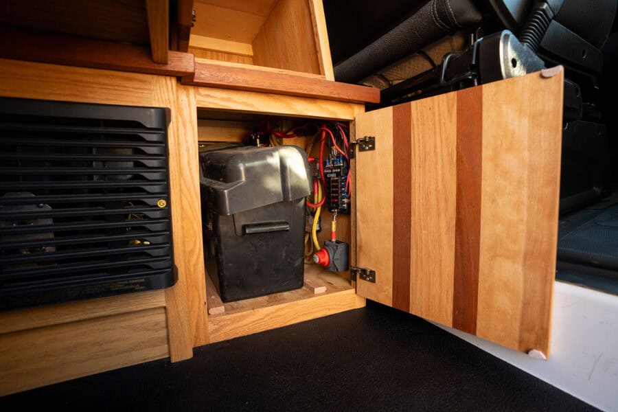 Electrical system with battery and wiring inside a camper van for off-grid living.