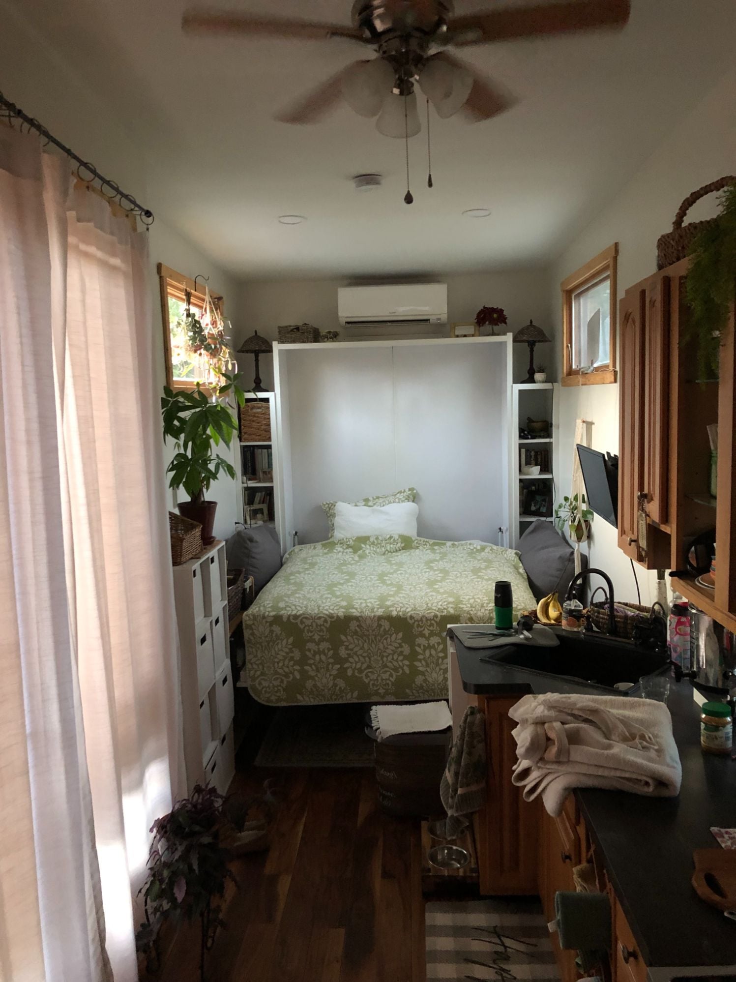 The hydraulic Murphy bed deployed over the couch in the Kangaroo tiny house, showing the queen mattress in sleeping position