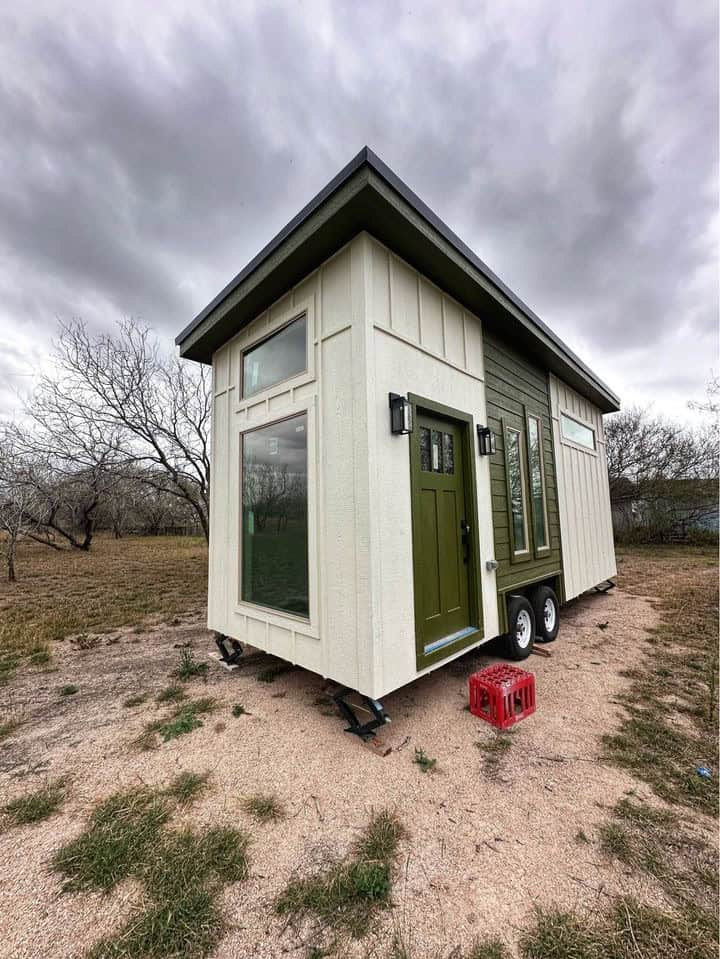 Compact tiny house with green accents and double loft bedrooms for efficient small space living.