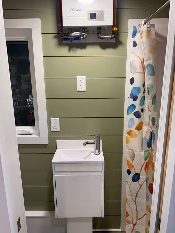 Compact tiny house bathroom with a modern sink and colorful shower curtain.