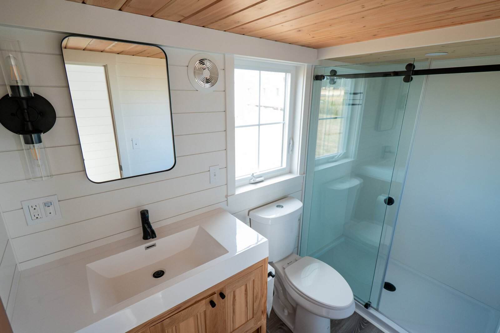 Villa Max bathroom with wood vanity, black-framed mirror and glass shower door