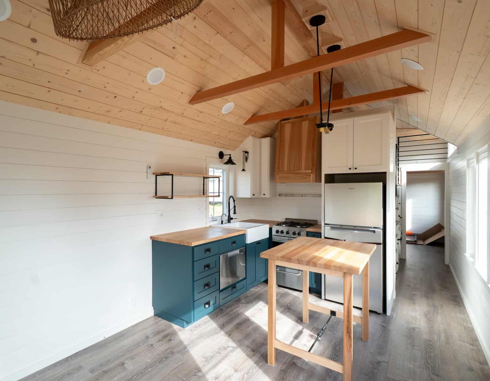 Villa Max kitchen with teal cabinets, butcher-block counters, stainless fridge and island under a vaulted pine ceiling