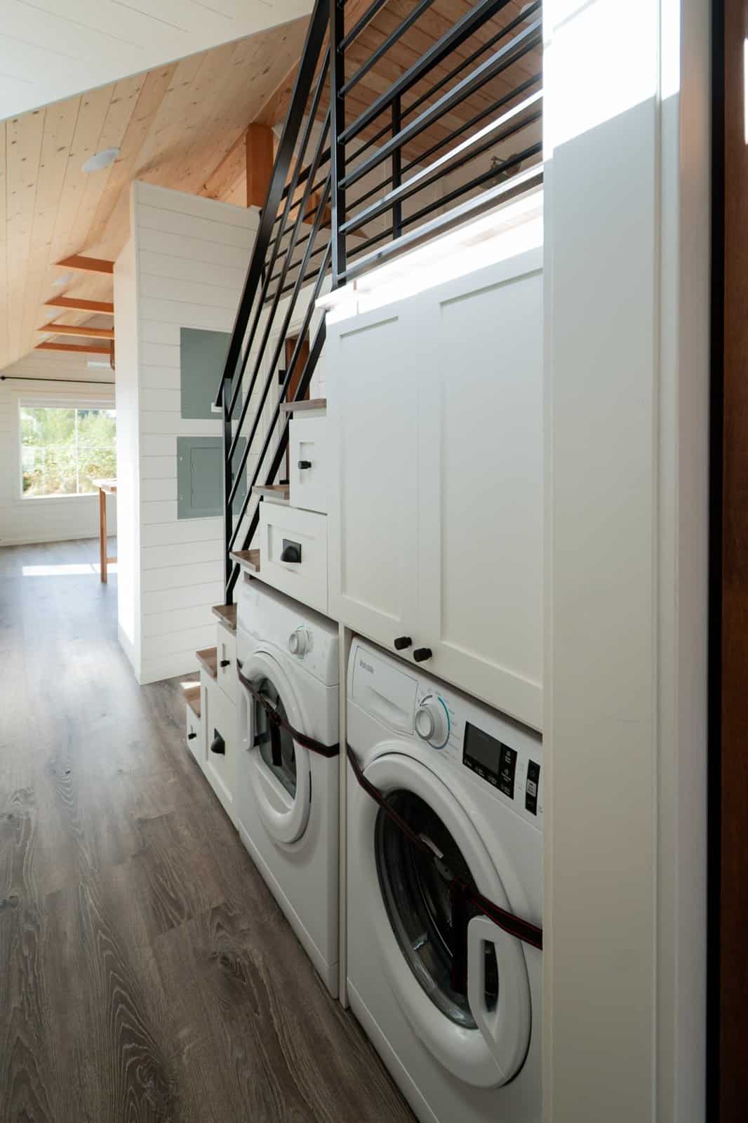 Staircase with built-in drawers, cabinets and a stacked washer and dryer