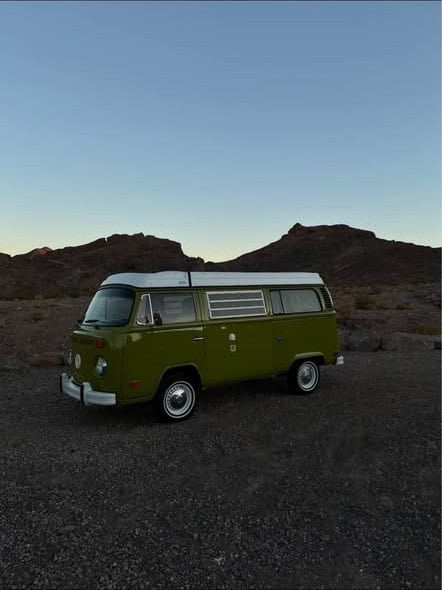 Side view of the bus parked on gravel with desert hills behind