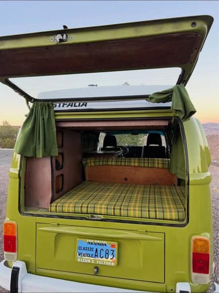 Rear hatch open to the plaid rear bed platform and Westfalia lettering on the pop-top