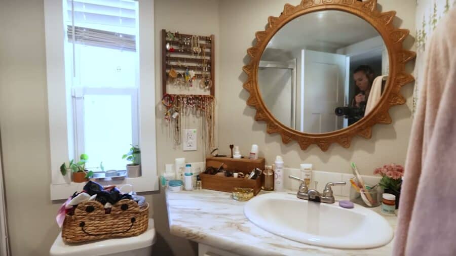 Tiny house bathroom vanity with a round sunburst mirror and jewelry organizer by the window