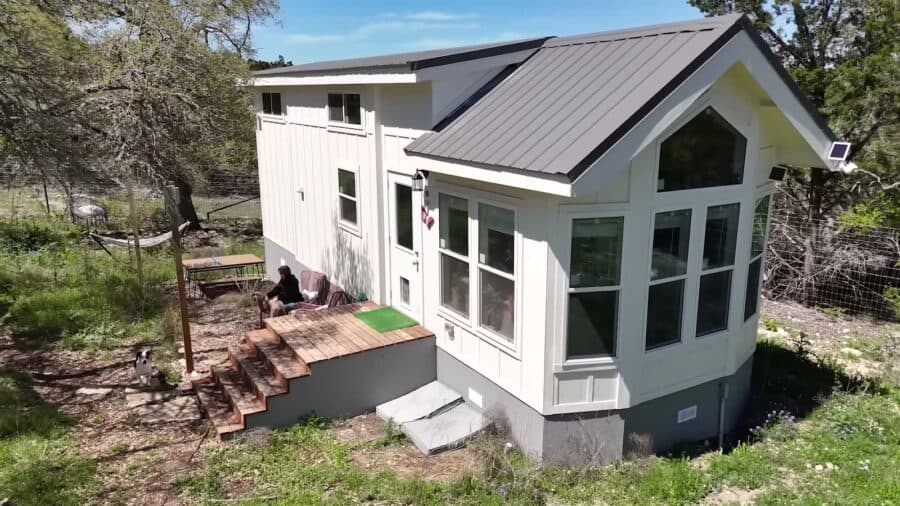 White tiny house with bay windows and a metal roof at Alveus Sanctuary in Texas