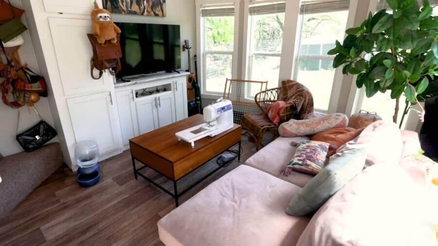 Tiny house living room with pink sectional sofa, wood coffee table and sewing machine