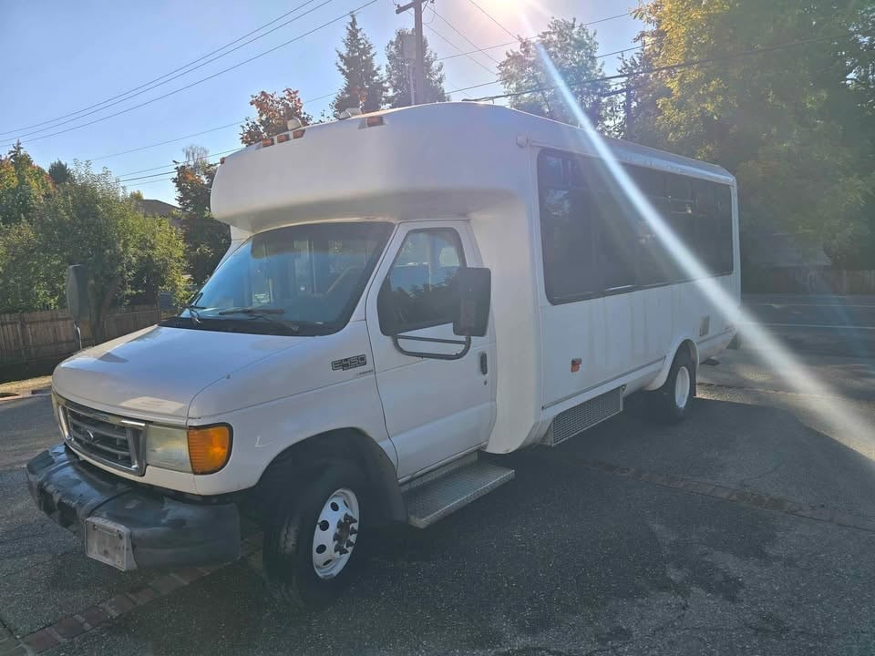 Front of the white Ford E450 shuttle bus in afternoon sun