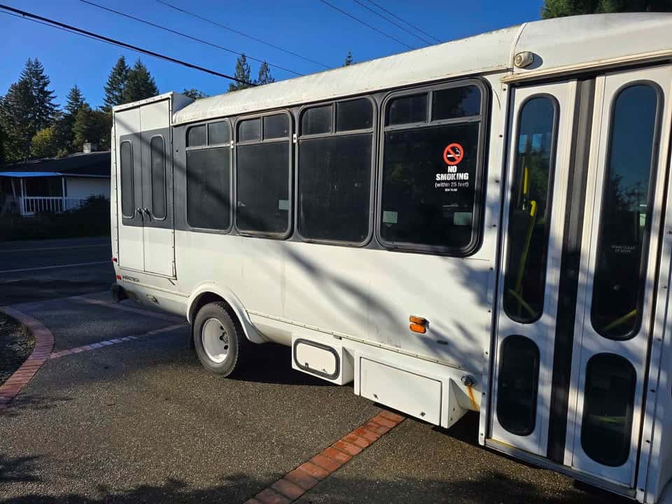 Passenger side of the shuttle bus with folding entry doors and a row of windows