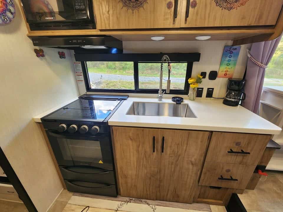 Kitchen with a three-burner range and oven, deep sink, wood-look cabinets, and a window