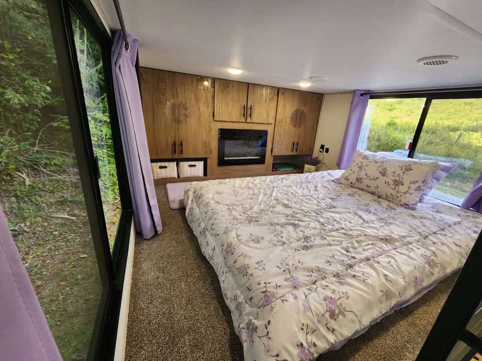 Loft bedroom with a full-size mattress, built-in cabinets, an electric fireplace, and windows on both sides