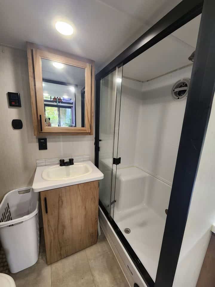Bathroom with a walk-in shower, vanity, and wood-framed mirror