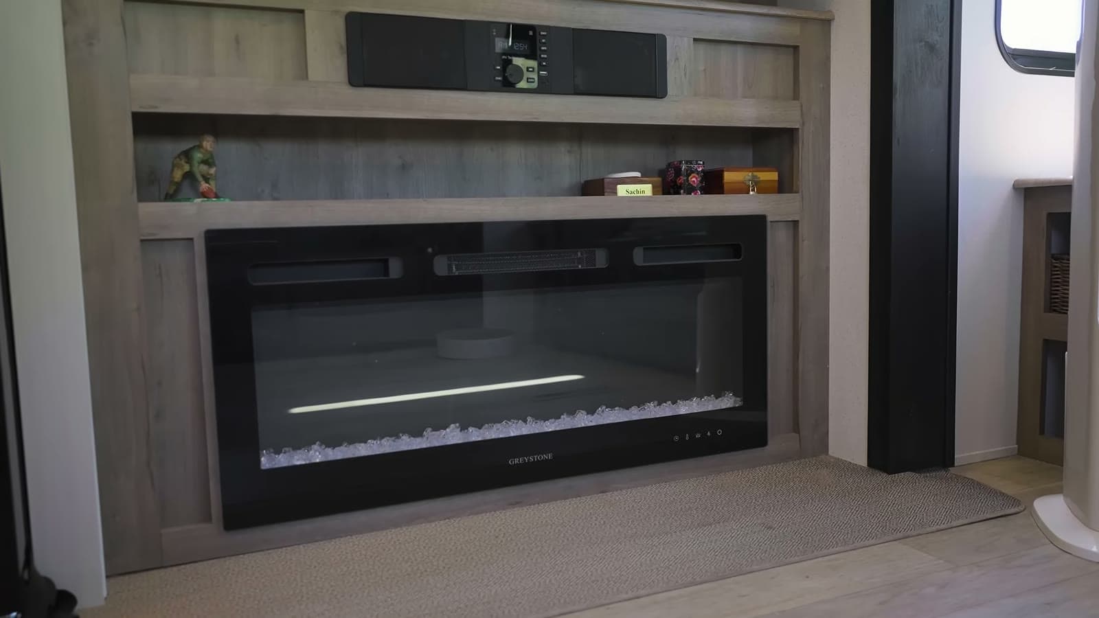 Built-in electric fireplace with a soundbar and shelves in a wood-grain entertainment center
