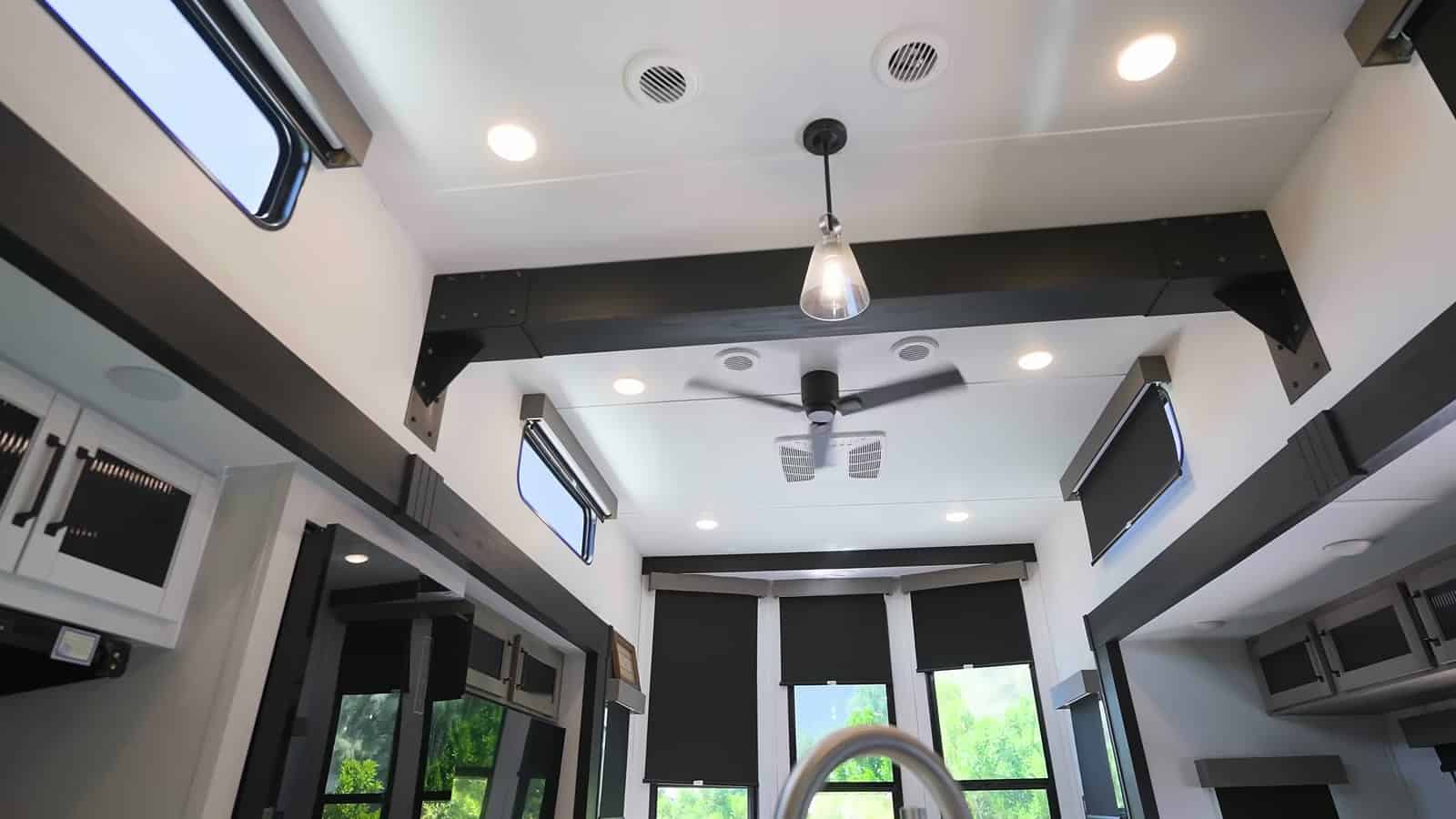 High ceiling with dark beams, a ceiling fan, pendant light, and clerestory windows in the trailer living area