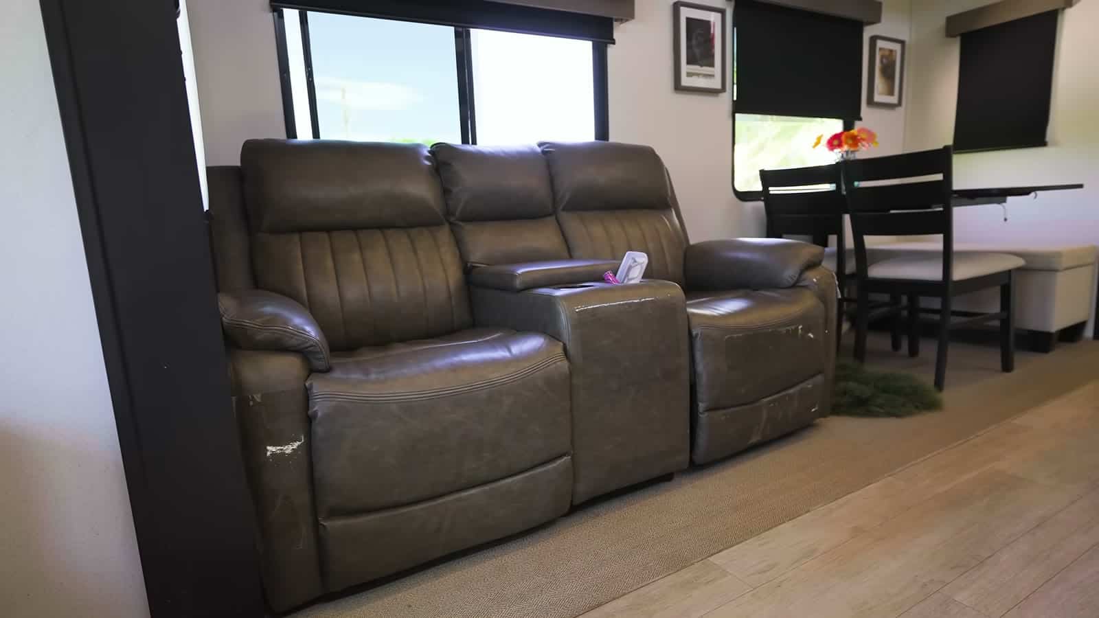 Brown leather reclining sofa with a center console next to a dining table and chairs