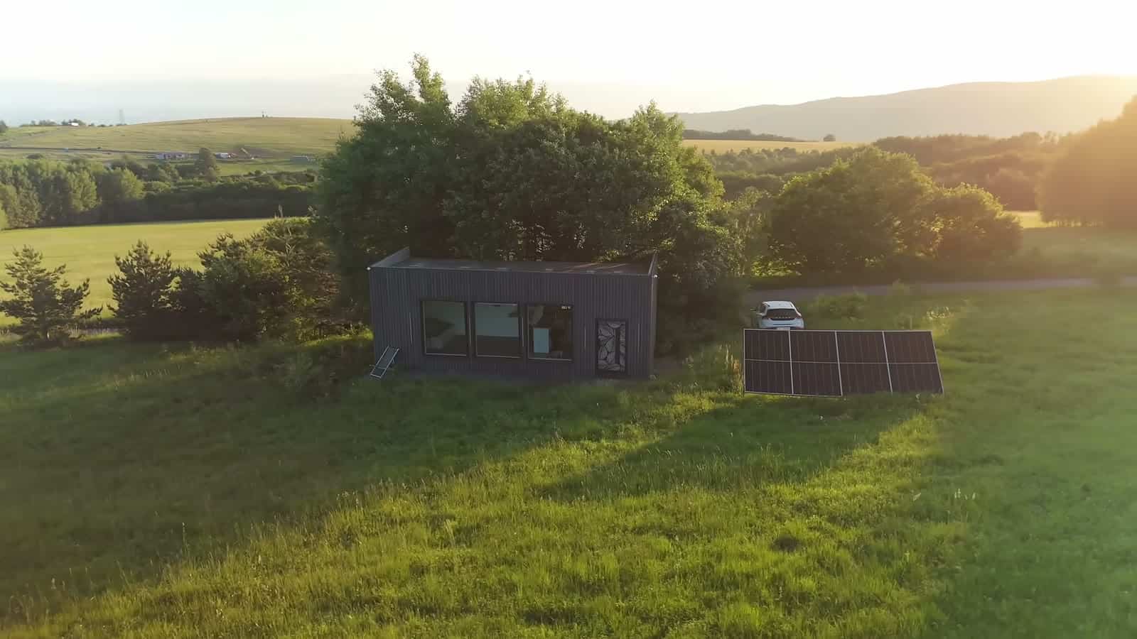 Aerial view at sunset of the studio and solar array among trees and rolling Bulgarian hills