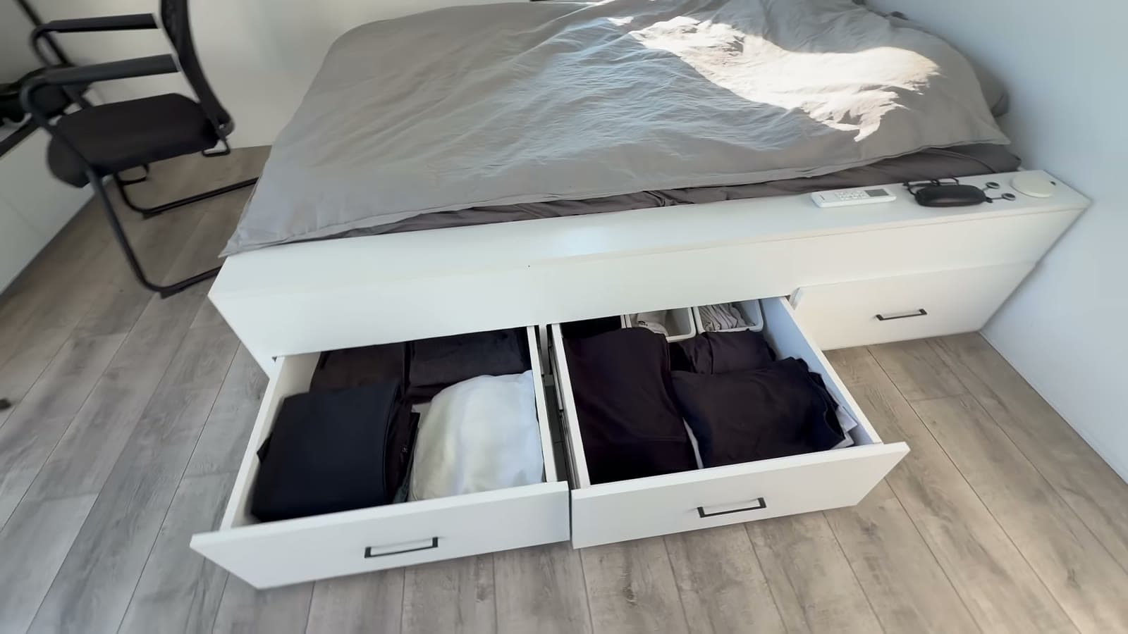 Platform bed with two large pull-out drawers full of folded clothes