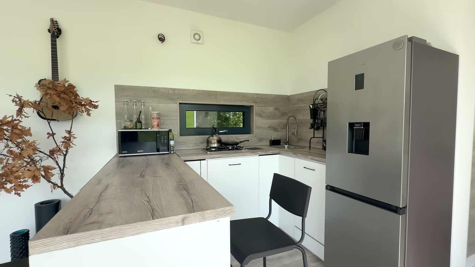 L-shaped kitchen with wood-look counters, a full-size refrigerator, microwave, and a small window over the stove
