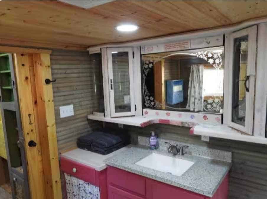 Pink bathroom vanity with granite top, sink, and a mirrored medicine cabinet
