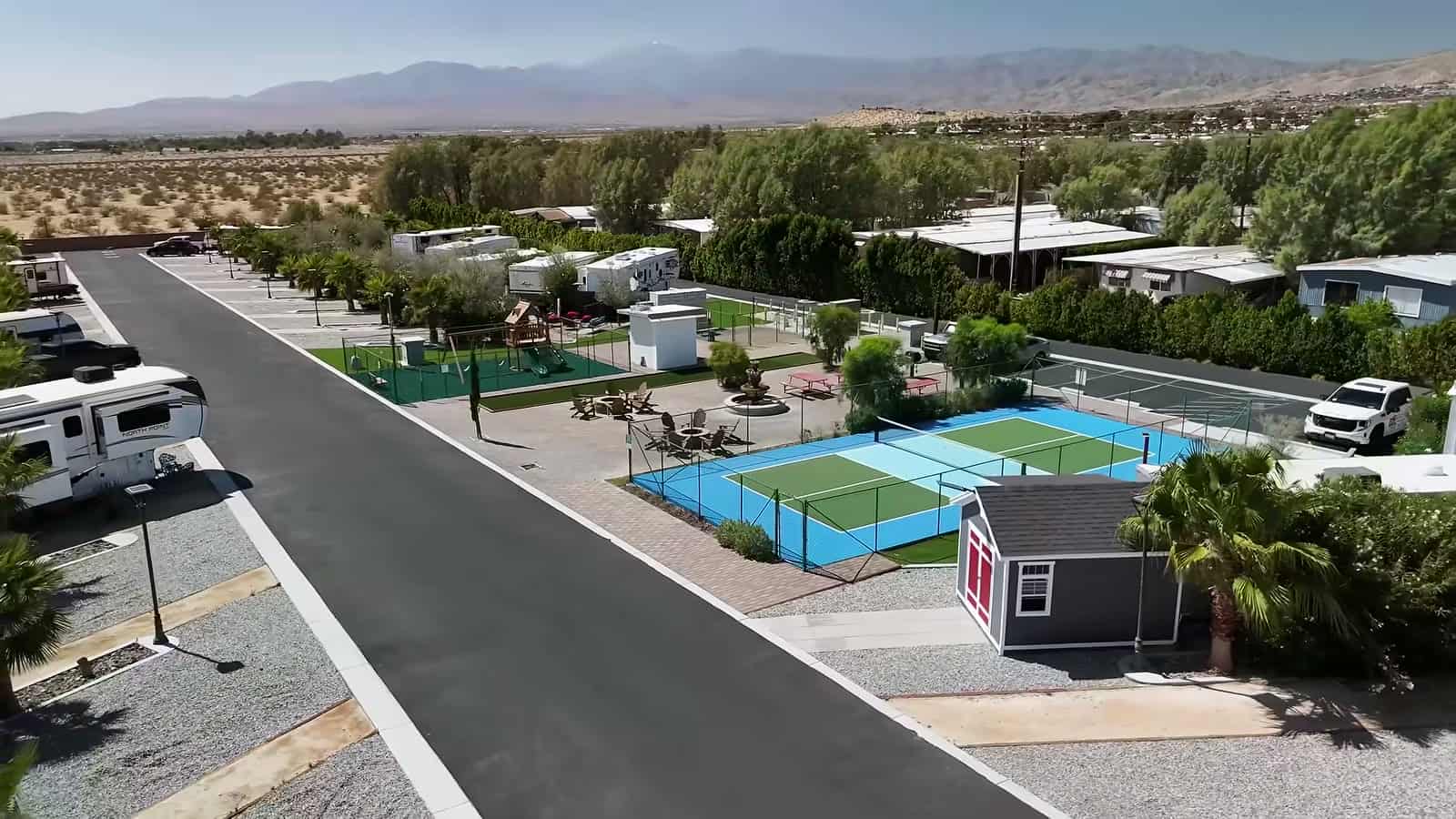 Aerial view of Paradise Tiny Home Community with pickleball courts, homes, and desert mountains beyond