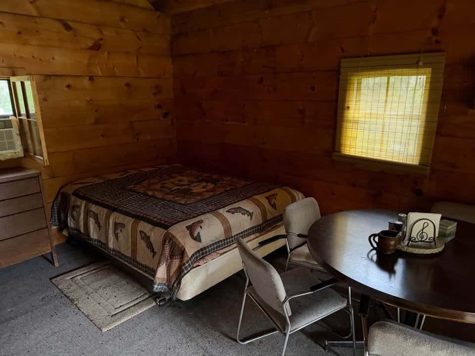 Bed and dresser on the main floor of the log cabin next to the dining table