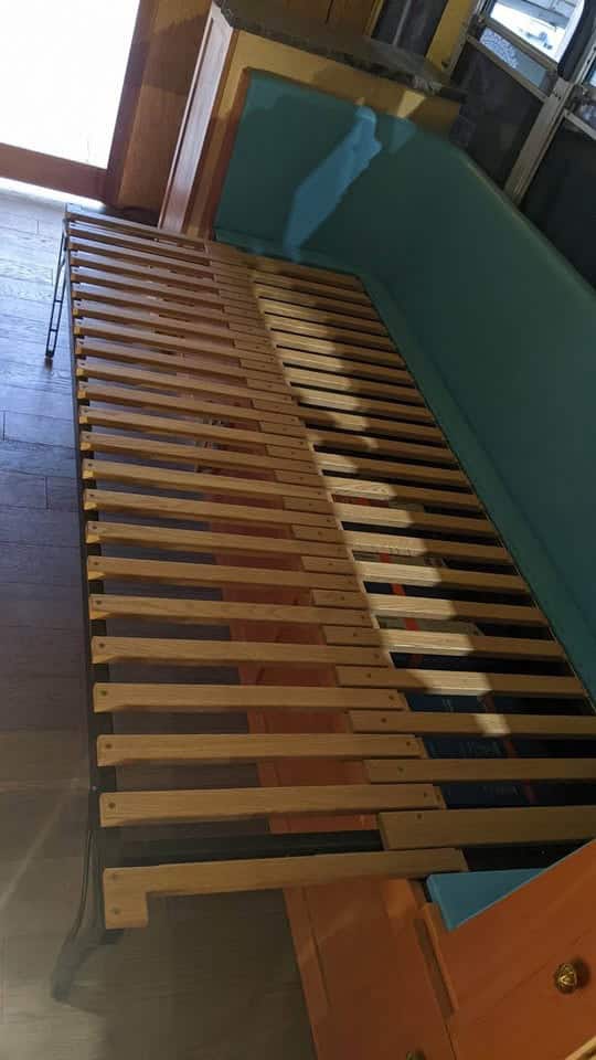 Pull-out wooden slat bed frame extended from the bench seat