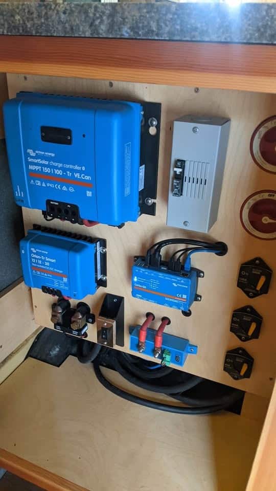 Victron solar charge controllers, inverter, and breakers mounted on a plywood panel
