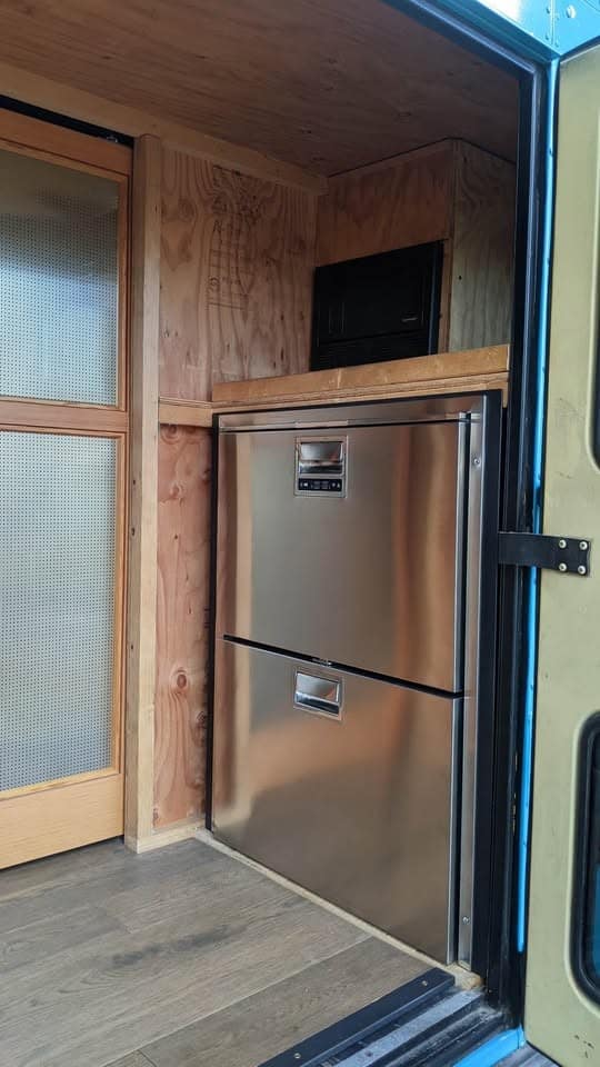 Stainless two-drawer marine refrigerator and freezer built into the wall by the door